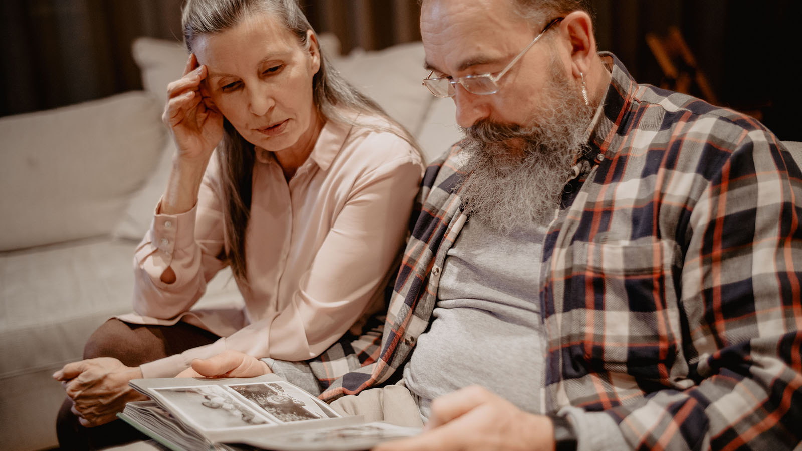 An older couple looking through a family photo album together at home