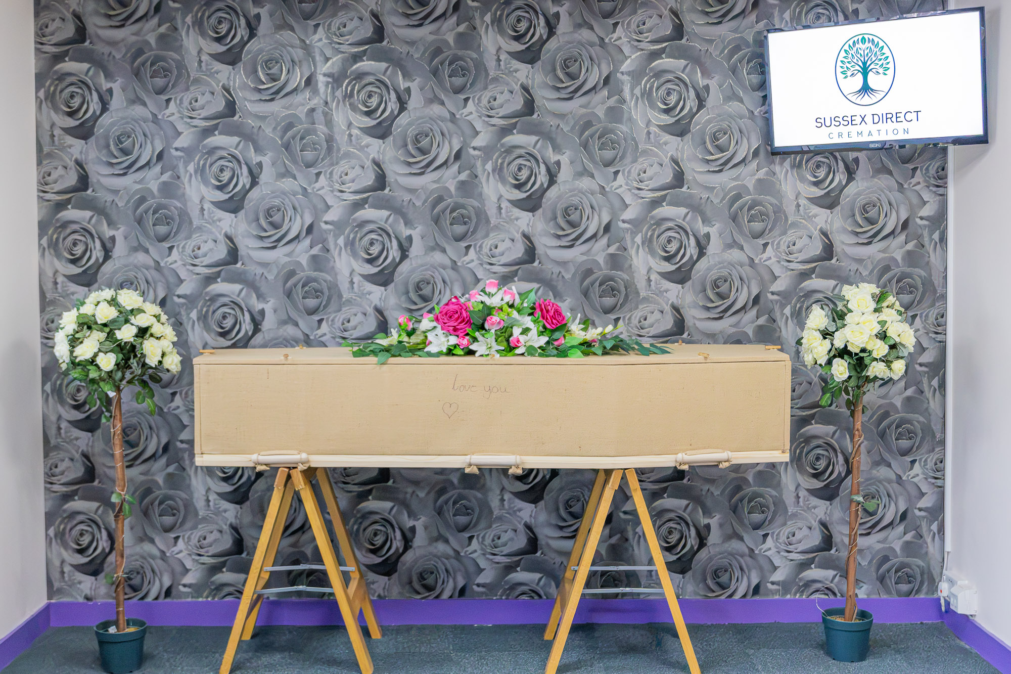 A natural jute coffin with floral tributes in the private chapel