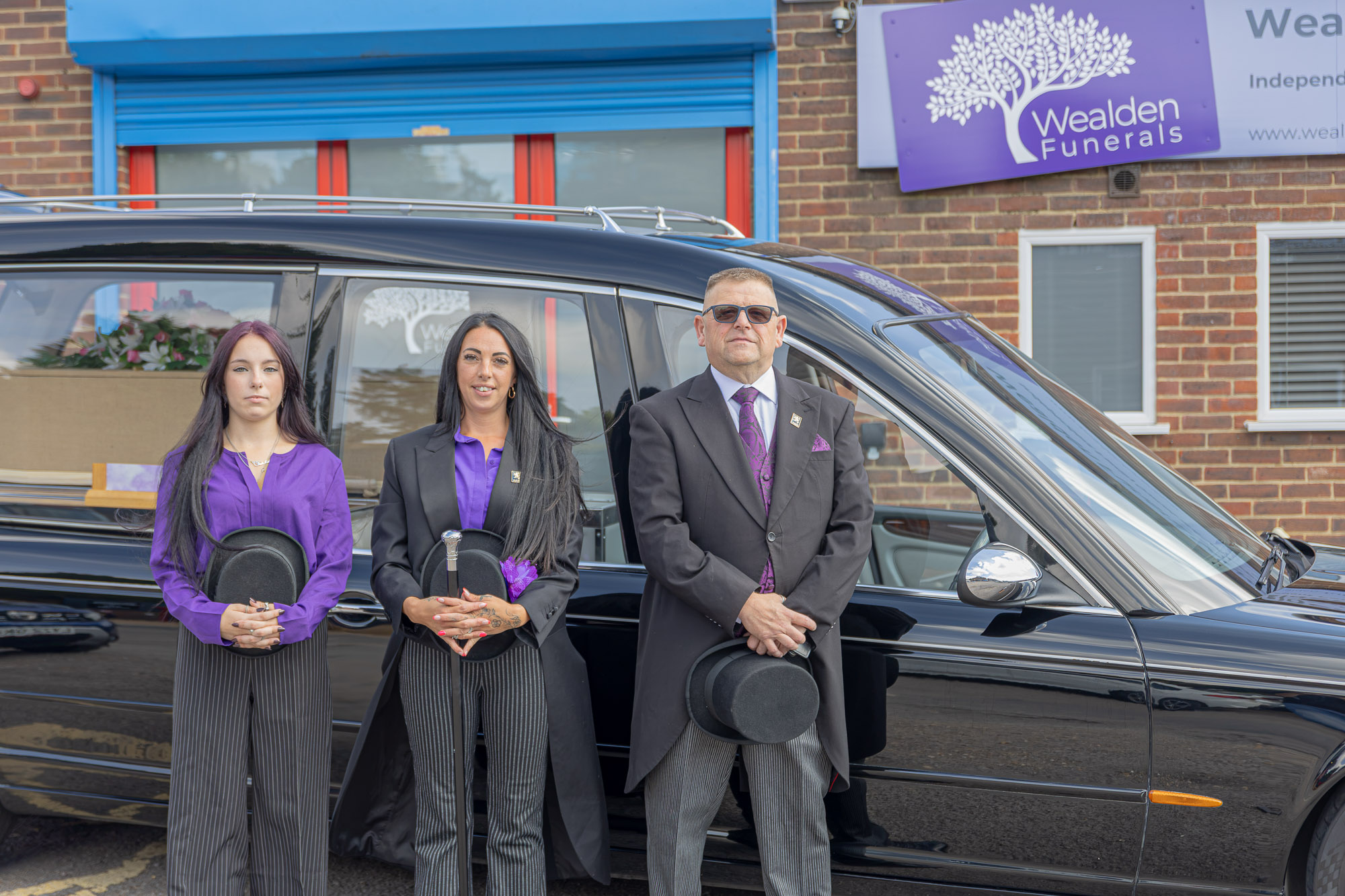 Tiah, Stacie and Andy beside the Wealden hearse outside the Heathfield office