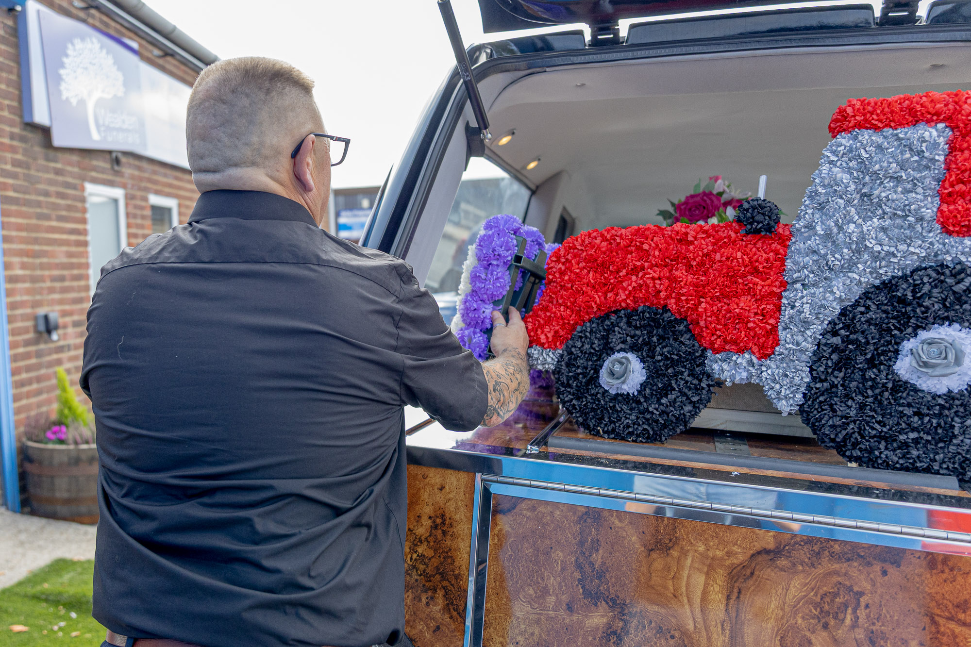 Andy placing a tractor-shaped floral tribute into the hearse