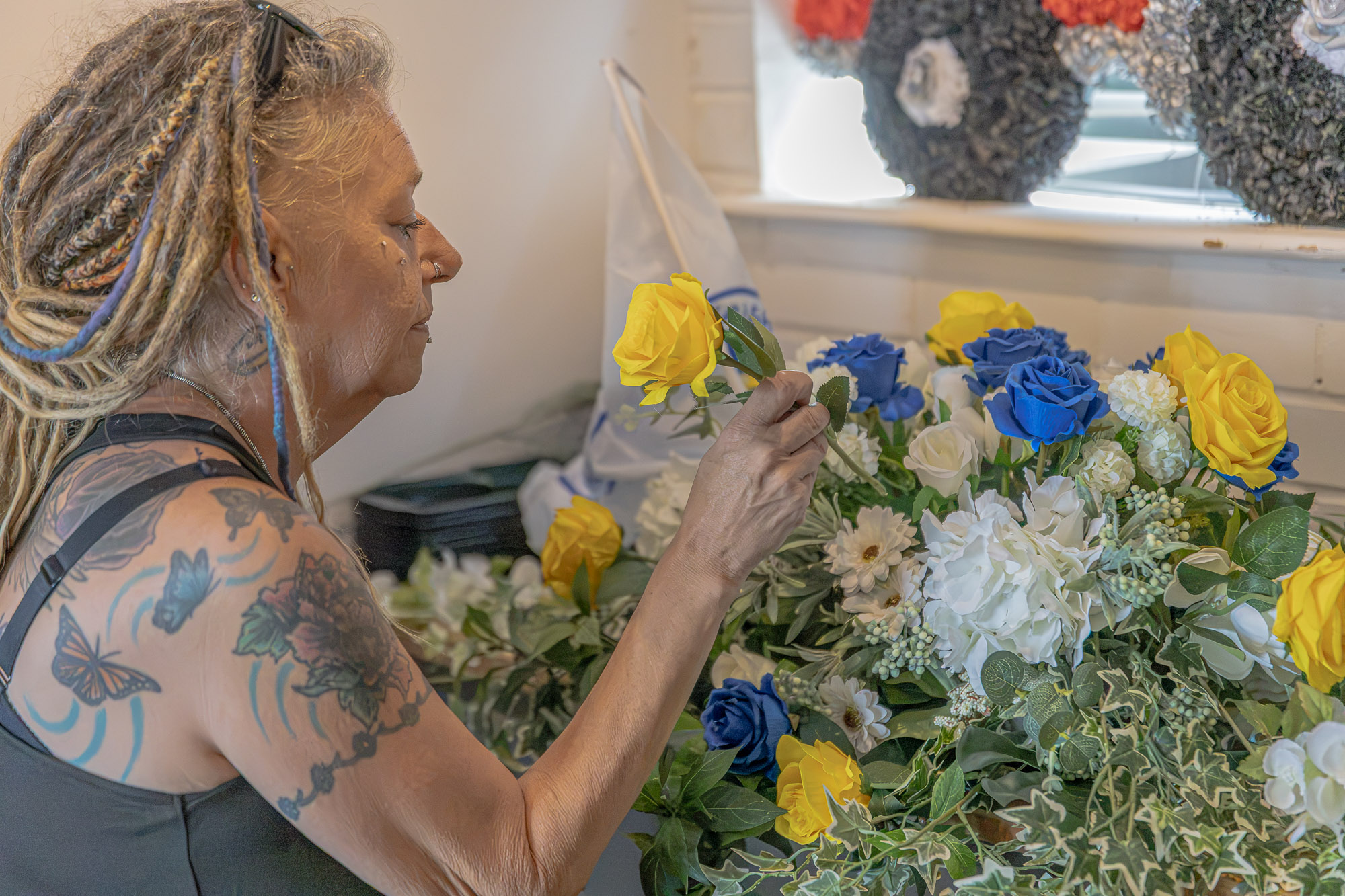 Nikkie arranging a blue, yellow and white floral tribute