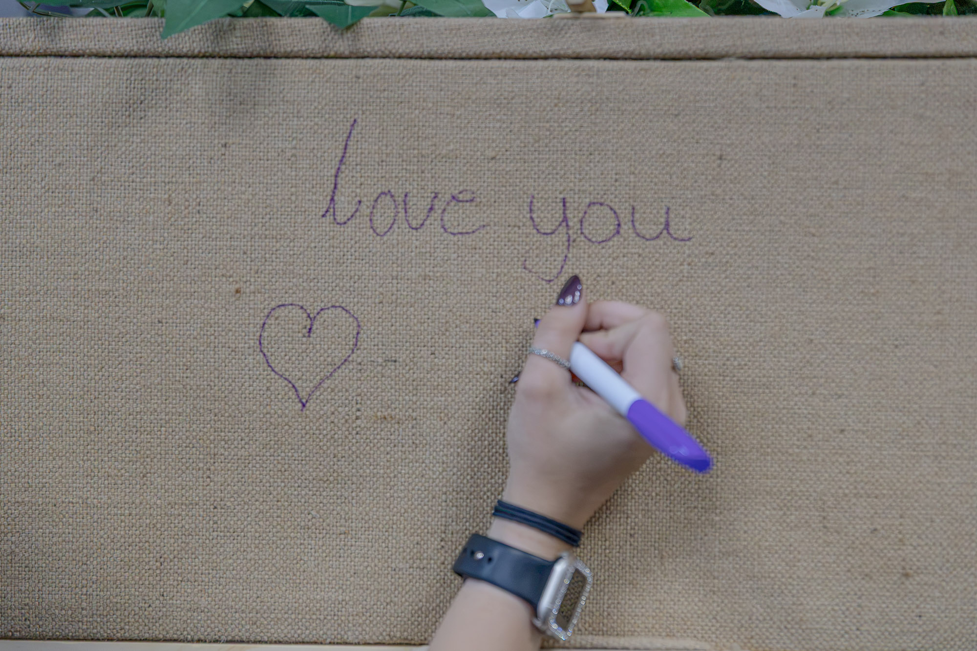 A personal handwritten message being added to a natural jute coffin