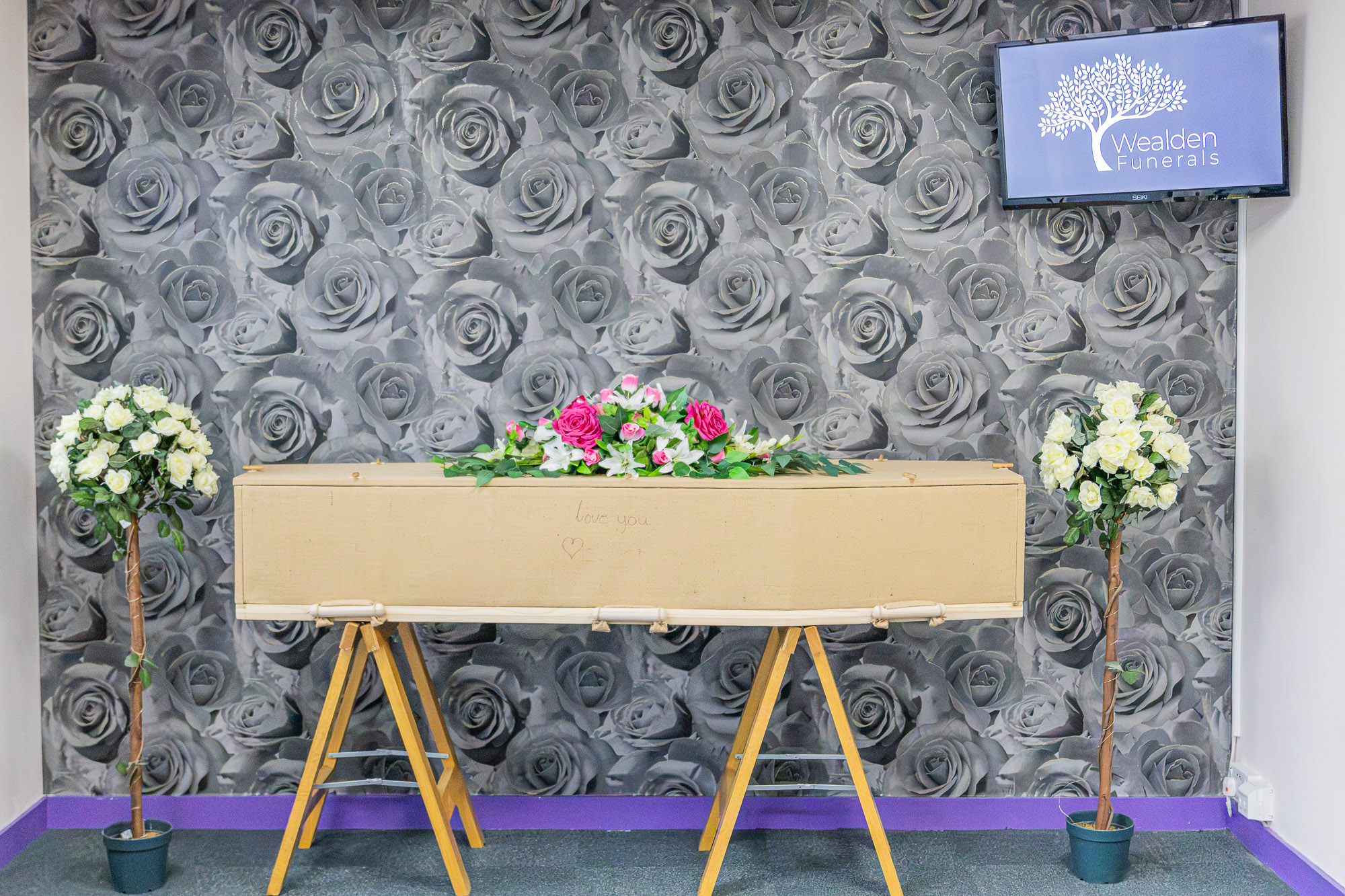 A natural jute coffin with loose floral tributes in the private chapel